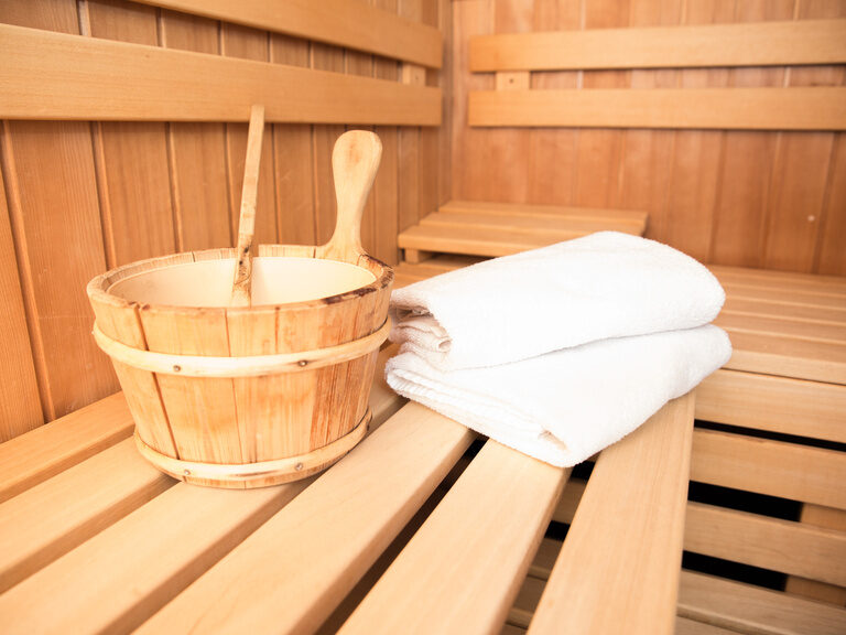Auf einer Saunabank steht ein Eimer neben Handtüchern